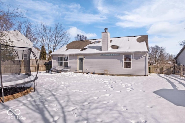 snow covered rear of property with a trampoline