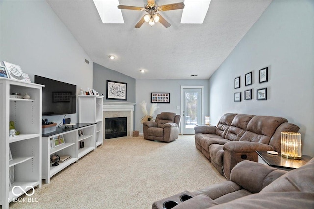 carpeted living room with ceiling fan, lofted ceiling with skylight, and a textured ceiling