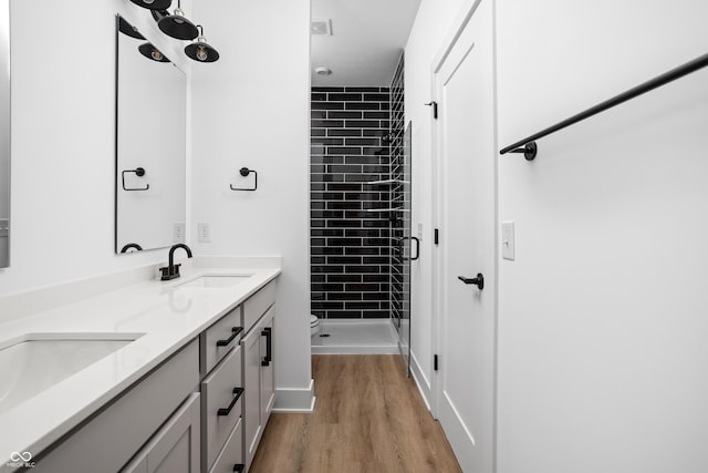 bathroom featuring vanity, wood-type flooring, tiled shower, and toilet