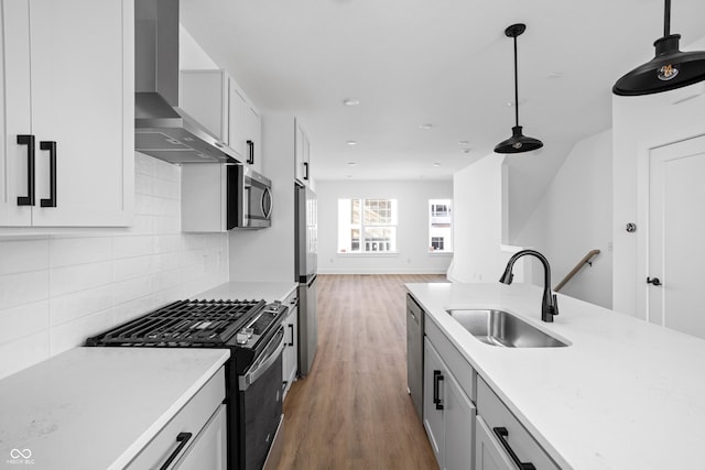 kitchen featuring stainless steel appliances, dark wood-type flooring, pendant lighting, wall chimney exhaust hood, and sink