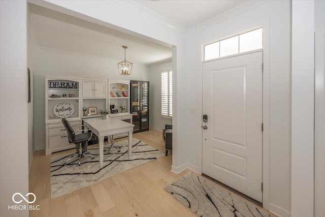 foyer with a notable chandelier, ornamental molding, and light hardwood / wood-style floors