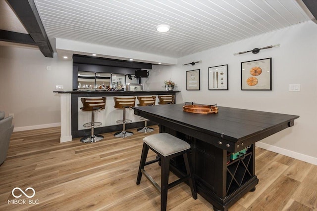 bar with beamed ceiling and light hardwood / wood-style floors