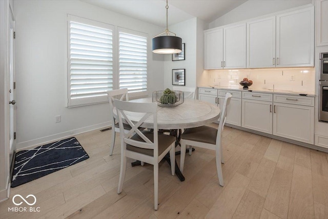 dining room with light hardwood / wood-style flooring and vaulted ceiling