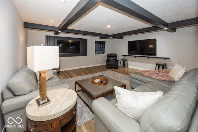 living room with wood-type flooring, beamed ceiling, and a textured ceiling