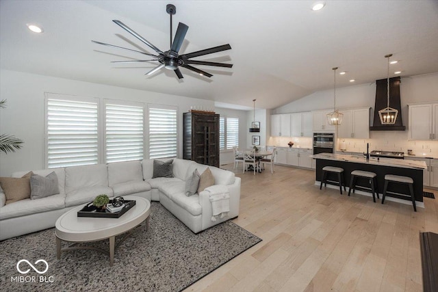 living room with light hardwood / wood-style floors, lofted ceiling, and ceiling fan