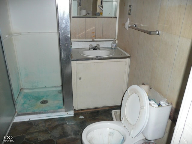 bathroom with walk in shower, wood walls, vanity, and toilet