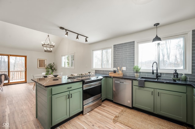 kitchen featuring pendant lighting, green cabinets, stainless steel appliances, light wood-type flooring, and sink