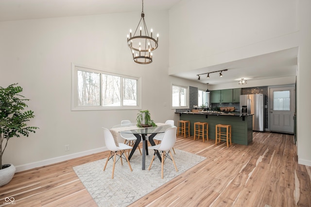 dining room with light hardwood / wood-style floors, sink, a chandelier, and a high ceiling