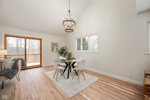 dining space with a notable chandelier, high vaulted ceiling, light hardwood / wood-style floors, and a wealth of natural light