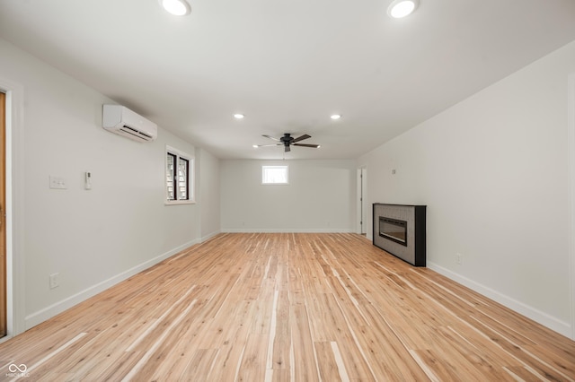 basement with ceiling fan, light wood-type flooring, and a wall mounted AC