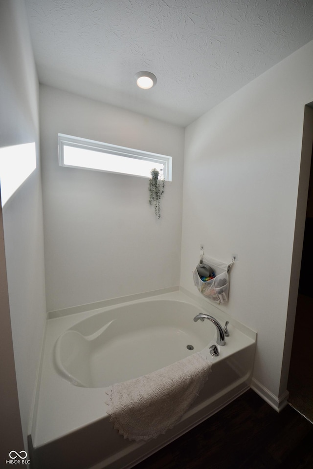 bathroom featuring a textured ceiling, a tub to relax in, and plenty of natural light