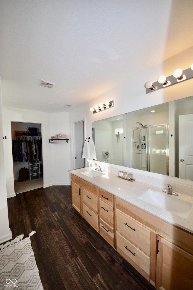 bathroom with vanity, a shower with shower door, and hardwood / wood-style floors