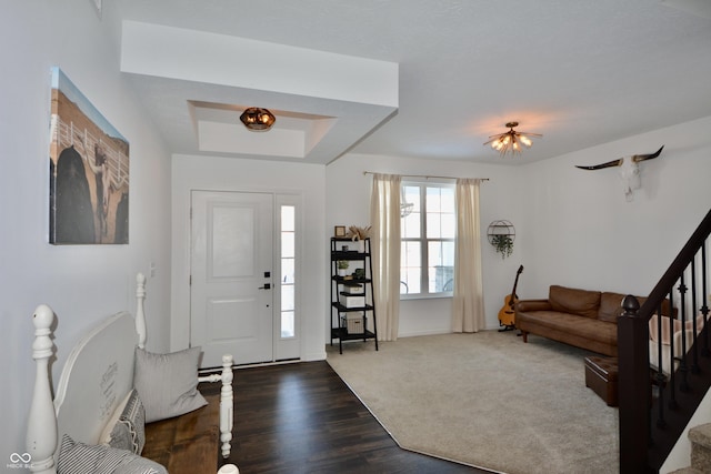 carpeted foyer with a raised ceiling