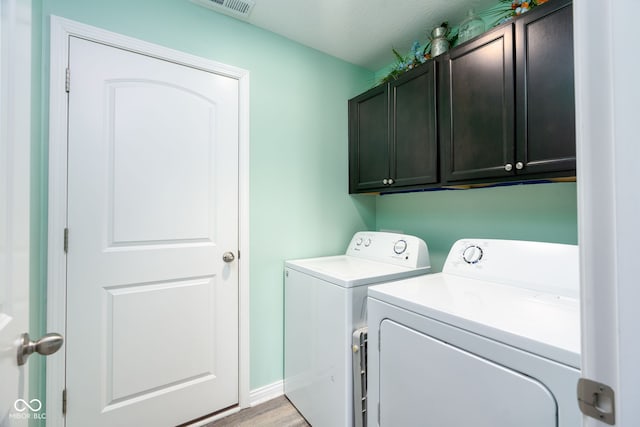 laundry area featuring cabinets, washer and dryer, and light hardwood / wood-style flooring