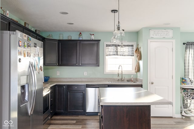 kitchen with stainless steel appliances, dark brown cabinets, wood-type flooring, a kitchen island, and sink