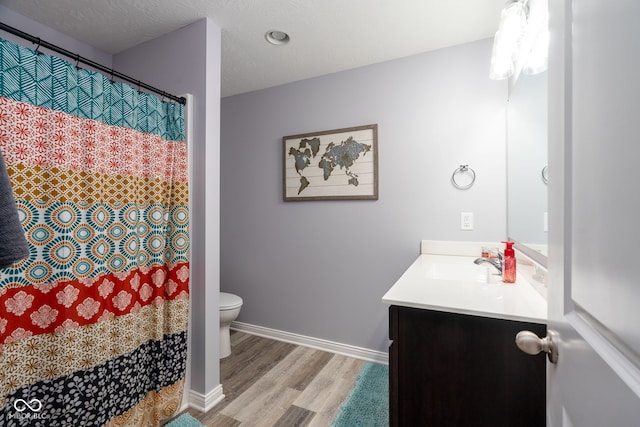 bathroom with toilet, vanity, a textured ceiling, and hardwood / wood-style flooring