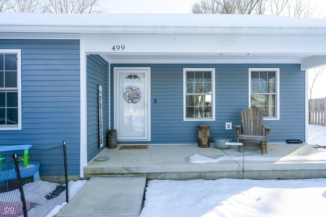 snow covered property entrance featuring a porch