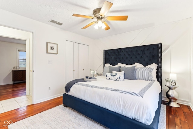 bedroom with wood-type flooring, ceiling fan, a textured ceiling, and a closet