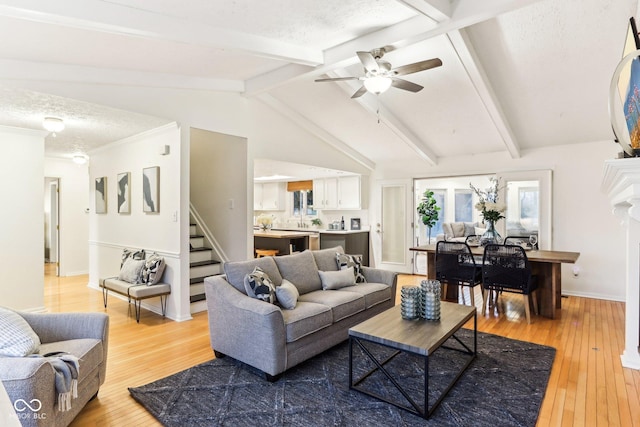 living room featuring ceiling fan, wood-type flooring, a textured ceiling, and vaulted ceiling with beams