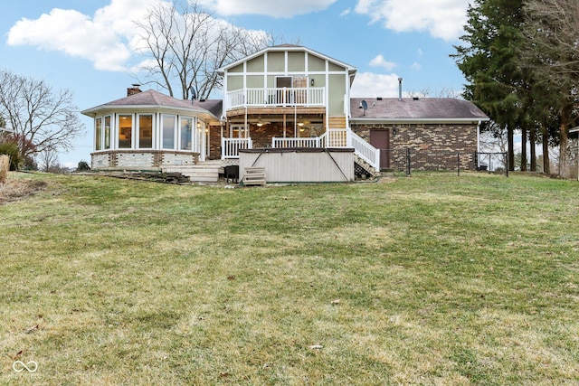 back of house featuring a wooden deck, a yard, and a sunroom