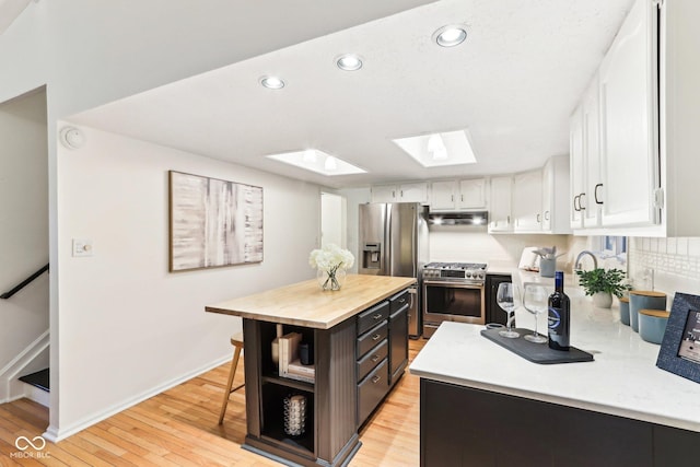 kitchen with butcher block countertops, a skylight, white cabinets, and appliances with stainless steel finishes