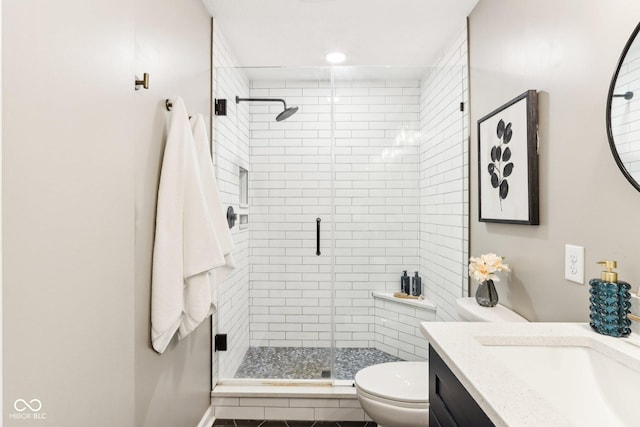 bathroom featuring vanity, toilet, and a shower with shower door