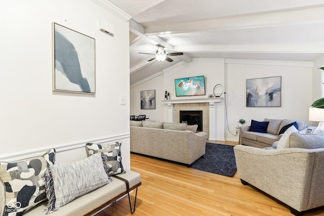 living room featuring a tiled fireplace, vaulted ceiling with beams, hardwood / wood-style floors, and ceiling fan