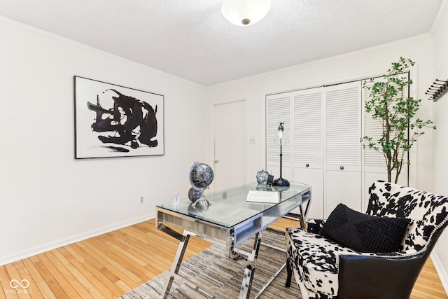 office with hardwood / wood-style floors, ornamental molding, and a textured ceiling