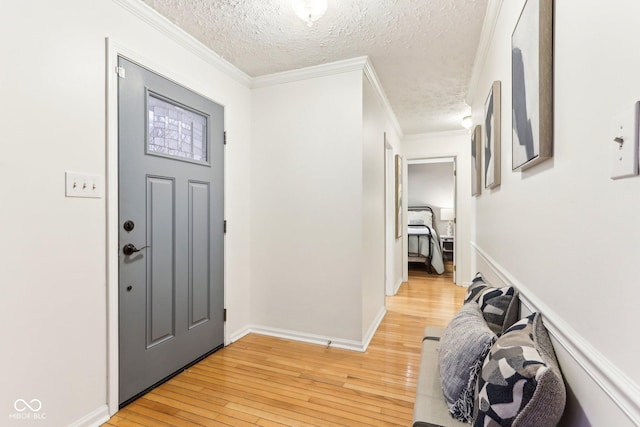 entryway with crown molding, light hardwood / wood-style floors, and a textured ceiling