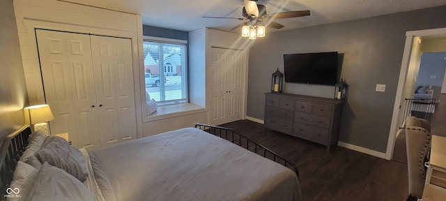 bedroom with ceiling fan, dark hardwood / wood-style flooring, multiple closets, and multiple windows