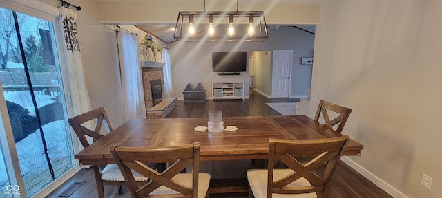 dining room with a brick fireplace and dark wood-type flooring