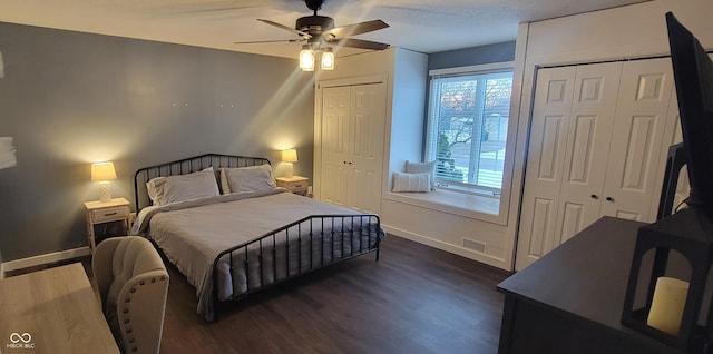 bedroom with dark hardwood / wood-style flooring, multiple windows, multiple closets, and ceiling fan