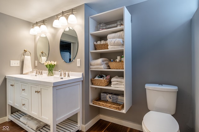 bathroom with toilet, vanity, and hardwood / wood-style floors