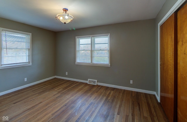 unfurnished bedroom with a closet, visible vents, baseboards, and hardwood / wood-style flooring