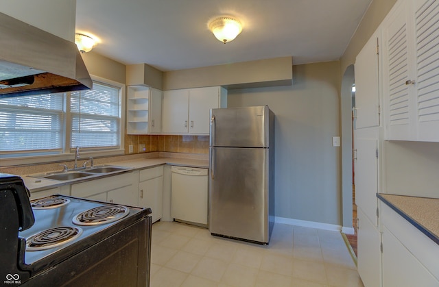 kitchen with arched walkways, freestanding refrigerator, a sink, island range hood, and dishwasher