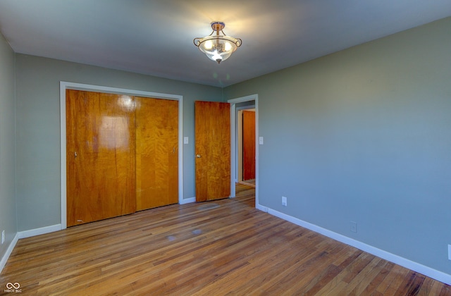 unfurnished bedroom featuring a closet, baseboards, and wood finished floors