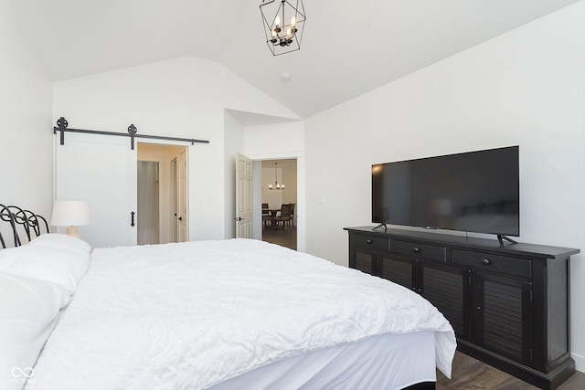 bedroom with a chandelier, dark wood-style flooring, a barn door, and vaulted ceiling