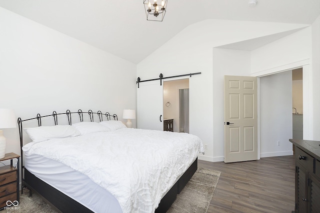 bedroom featuring a barn door, lofted ceiling, baseboards, and dark wood finished floors