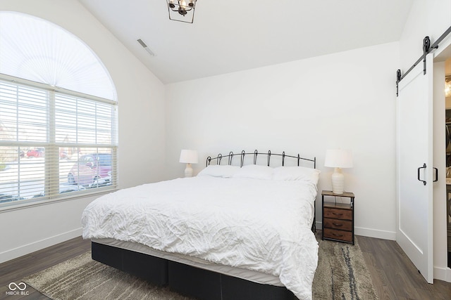 bedroom featuring vaulted ceiling, baseboards, a barn door, and dark wood-style flooring