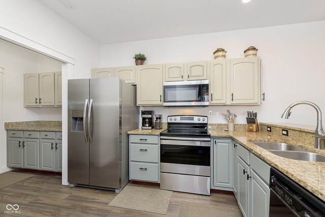 kitchen featuring a sink, stainless steel appliances, light stone countertops, and dark wood-style flooring