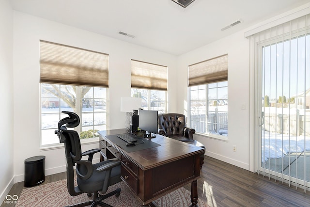 home office with dark wood finished floors, visible vents, and a wealth of natural light