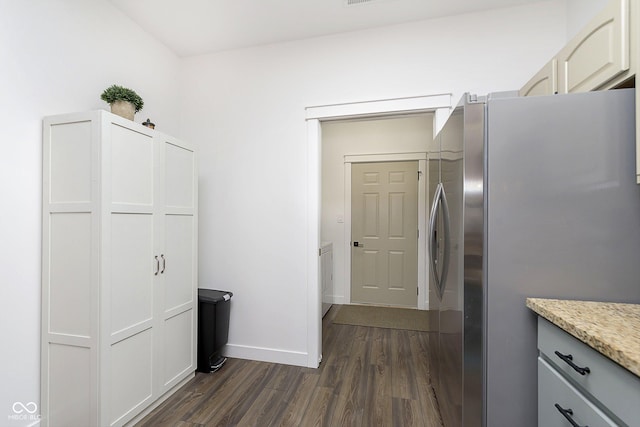 kitchen with light stone counters, baseboards, dark wood finished floors, and freestanding refrigerator