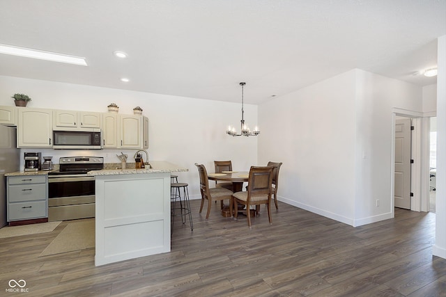 kitchen with baseboards, a chandelier, pendant lighting, appliances with stainless steel finishes, and dark wood-style floors