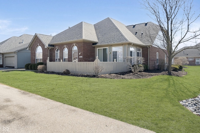 view of front of home featuring brick siding, a front lawn, and roof with shingles