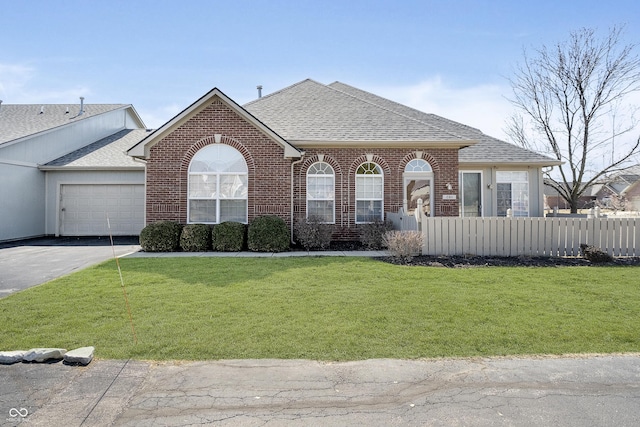 view of front facade featuring aphalt driveway, brick siding, a fenced front yard, and roof with shingles