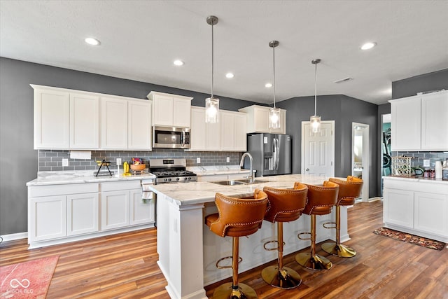 kitchen with stainless steel appliances, white cabinetry, hanging light fixtures, and sink