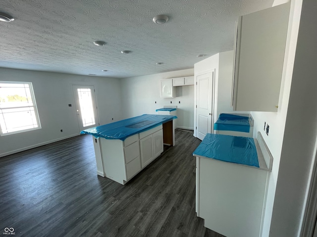 kitchen featuring dark hardwood / wood-style flooring, white cabinetry, a textured ceiling, and a center island