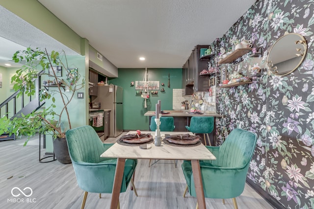 dining space with a textured ceiling and light hardwood / wood-style floors