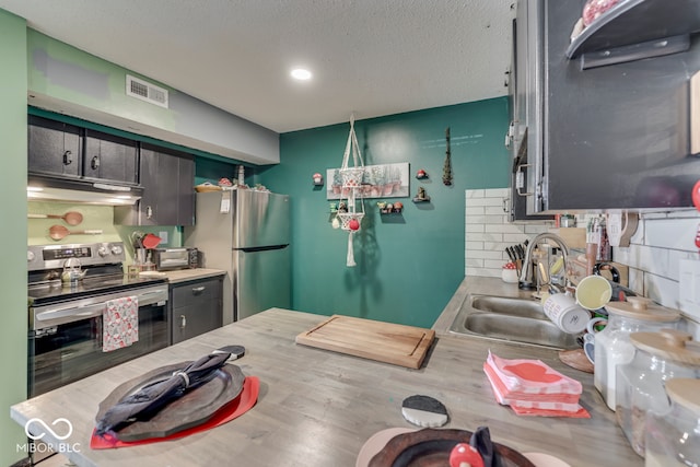 kitchen featuring a textured ceiling, appliances with stainless steel finishes, tasteful backsplash, and sink