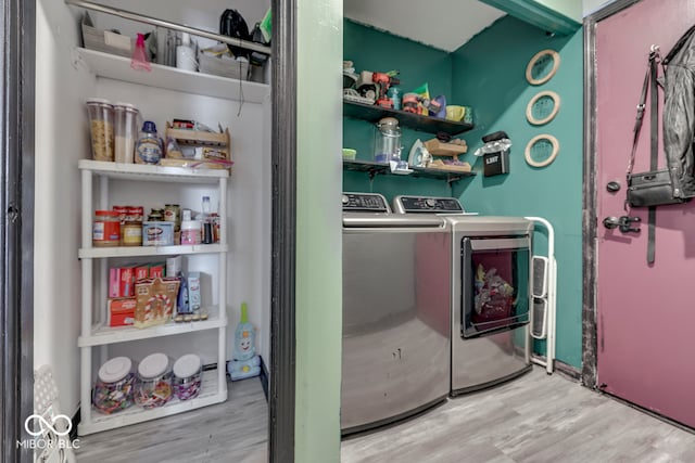 laundry area with washing machine and dryer and light hardwood / wood-style floors